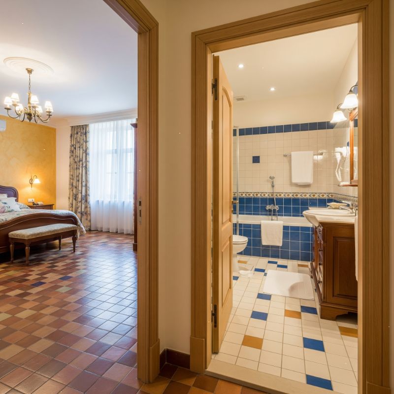 Flooring and tiling in Kolkata: Bedroom with terracotta-toned checkered floor and bathroom with blue and white tiles.