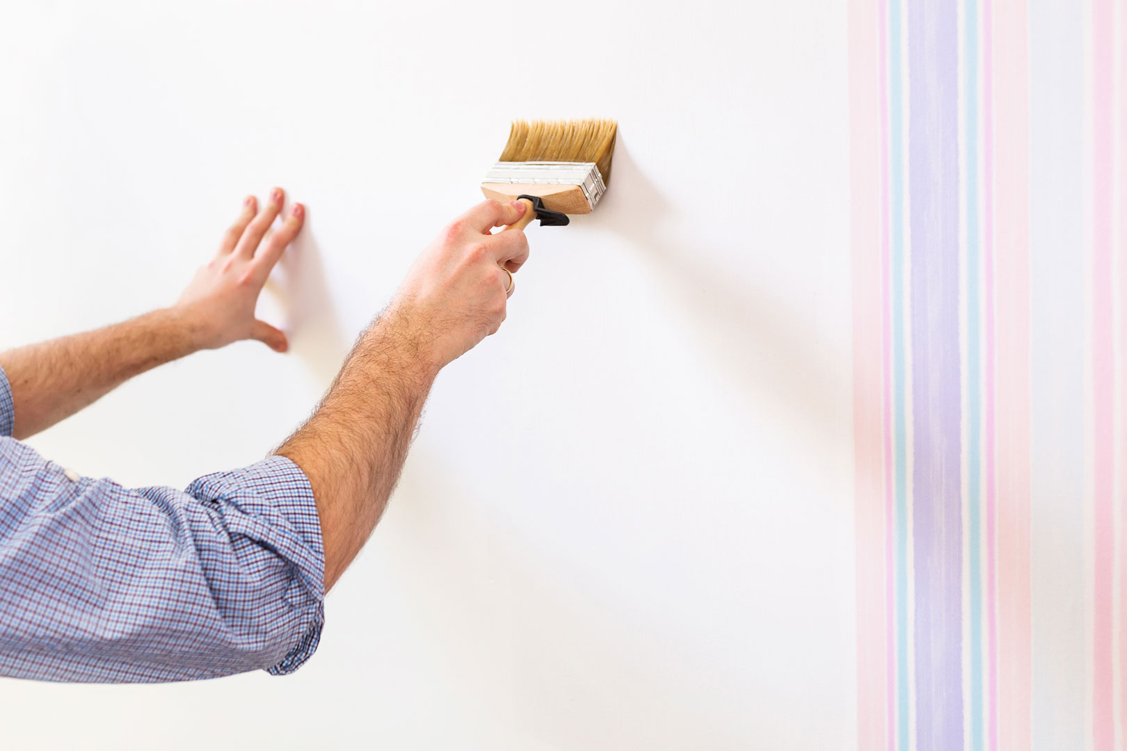 Man using a brush to cover wallpaper with paint.jpg